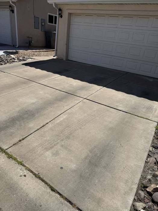Driveway and garage entrance before pressure washing, showing dirt and staining